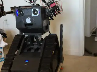 R.O.B. stands on its tracked base with both articulated arms raised in a home workshop.