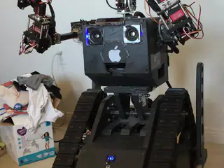 R.O.B. demonstrates head movement while holding both robotic arms raised beside its torso.