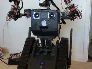 R.O.B. rotates its camera head above a tracked base while its arms remain lifted.