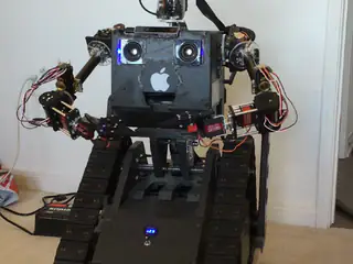 A builder places a decorated planter box across R.O.B.'s arms and adjusts it into position.