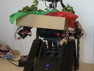 R.O.B.'s camera head pans above the foliage while the planter remains balanced across its arms.