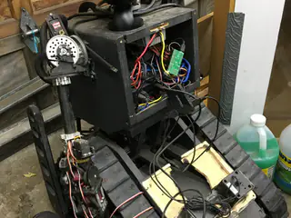 Open rear electronics bay and left arm of the tracked robot, with loose wiring visible inside.