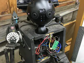 Spherical multicamera head mounted above the robot's exposed electronics bay and left shoulder assembly.
