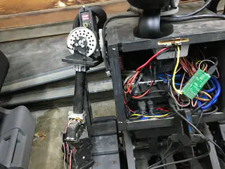 Close framing of the open electronics bay, loose red wiring, and vertically hanging left arm.