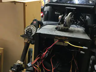 Upper electronics compartment with loose colored wires beneath a shoulder gear and partially cropped camera head.