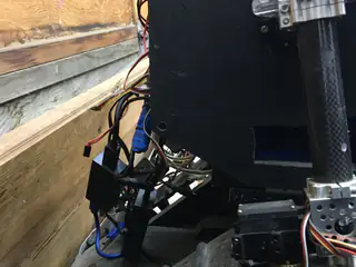 Tightly cropped lower side of the enclosure with wiring, a tread, and part of the arm actuator.