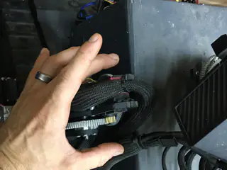 A hand beside a braided cable loop and toothed shoulder gear inside the robot housing.