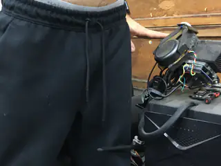 Cropped person standing beside the robot's exposed top wiring and a circular component resting forward.