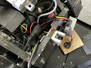 Top-down close-up of wiring, a motor, and wooden mounting pieces inside the robot's tracked chassis.