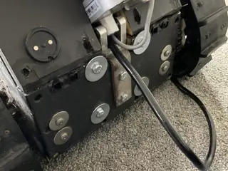 Angled view of the robot's rear drive panel, bolts, cable, and motor housing beside one tread.