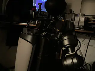 Wider dark view of both upper arm assemblies, the spherical head silhouette, and a blue monitor.