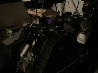 Dim overhead view of the tracked chassis, drive motor, exposed frame, and one mounted arm.