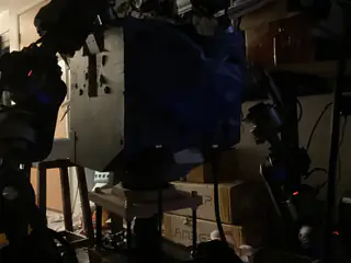 Dark side view of the robot's blue-covered torso with articulated arms flanking the enclosure.