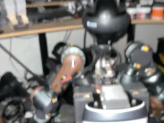 Out-of-focus frontal close-up of the spherical camera head and articulated shoulder mechanisms.
