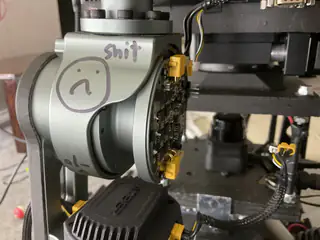 Wider view of the marked gray joint and attached circular circuit board amid the arm hardware.