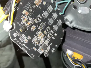 Close-up of the back of a round black circuit board with dense components and yellow connectors.