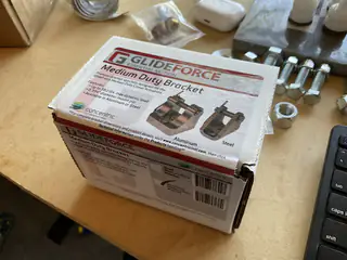 Boxed GlideForce medium-duty linear actuator on a workbench with loose bolts and hardware.