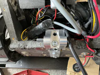 Aluminum cable clamp mounted inside the robot base among red, black, and gray wiring.