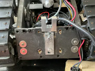 Centered front view of the bracket assembly secured to a black chassis plate amid wiring.