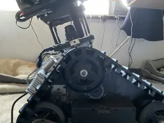 Low interior view of the tracked chassis showing a large sprocket, chain, and support bars.