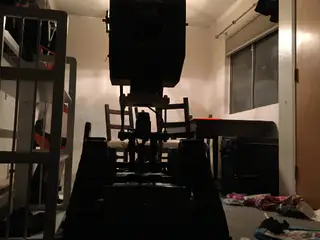 Backlit silhouette of the tracked robot in a dim room framed by a window and furniture.