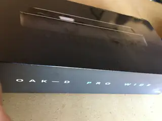 Black OAK-D Pro Wide camera box leaning against a reflective surface on carpet.