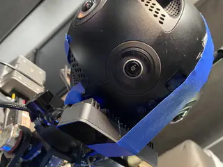 Close-up of the spherical multicamera head secured with blue painter's tape above paired sensors.