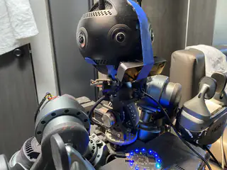 Angled upper-body view with taped spherical camera head, exposed neck wiring, and a jointed arm.