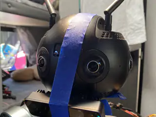Close right-side view of the spherical head showing two antennae, central lens, and vertical blue tape.
