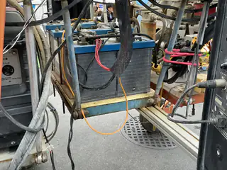 Large battery and bundled cables fill a close view inside an orange robot frame.