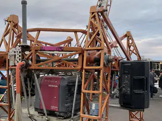 Orange open-frame machine holds a red Honda generator and black cylindrical components outdoors.