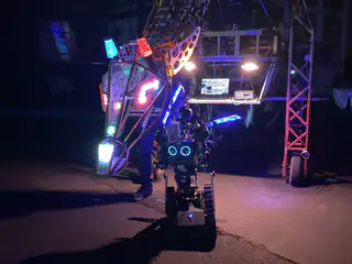 Multicolored dragon head hangs directly above a compact robot with glowing blue circular eyes.