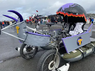 Whimsical three-wheeled vehicle combines a gray shark body, purple tentacles, and painted dome.