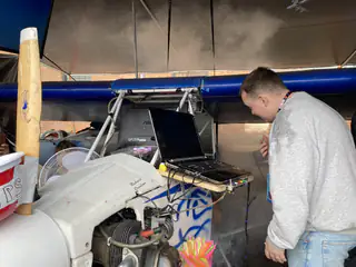 Person examines a monitor and exposed electronics mounted inside the small propeller-driven aircraft.
