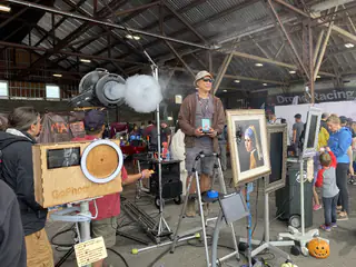 Thick fog pours from the round machine above the wooden selfie booth and framed portraits.