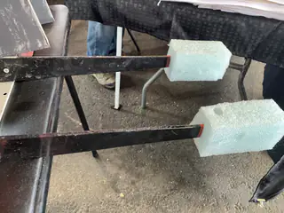 Light blue foam blocks cover the ends of two parallel black metal bars.
