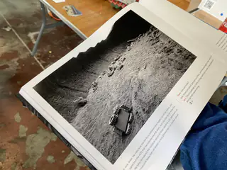 Close view of a book page showing a rover crossing textured, rocky terrain.
