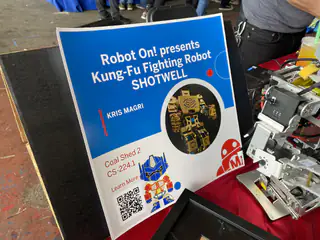 Kung-Fu Fighting Robot sign stands beside a partially visible gray humanoid robot.