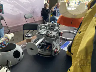 Open white droid chassis and detached round shell components cover a demonstration table.