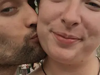 Close selfie shows one attendee kissing another attendee on the cheek.