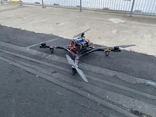 Wider side angle shows the four-armed multicopter parked beside a concrete curb.