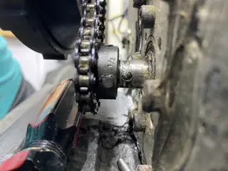 Hand tool positioned beside the tread chain and axle during drivetrain assembly.