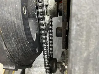 Narrow clearance between the tread wheel, drive chain, and chassis wall.