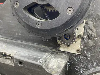 Exposed sprocket, chain, and wheel hub mounted above a newly machined chassis opening.