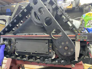 Side profile of the raised triangular tread frame with exposed wheels and chain drive.