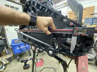 Hand steadies a digital measuring bar across the lower edge of the tread frame.