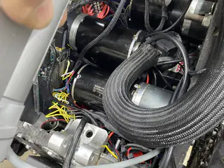 Dense internal routing of braided hoses, motors, connectors, and multicolored control wires.