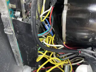 Multicolored wires routed beside a black cylindrical motor inside the robot chassis.