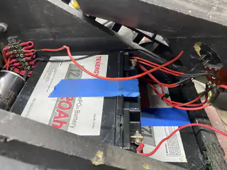 Two large batteries strapped into the chassis with red power leads and terminal blocks.