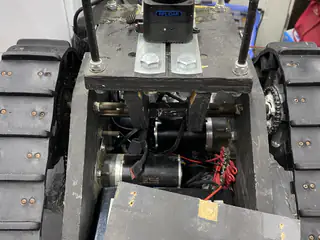 Overhead view of the open tracked base, exposing motors, wiring, and battery connections.